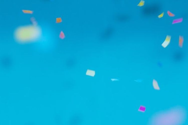 Buntes Konfetti fällt vor türkisem Hintergrund